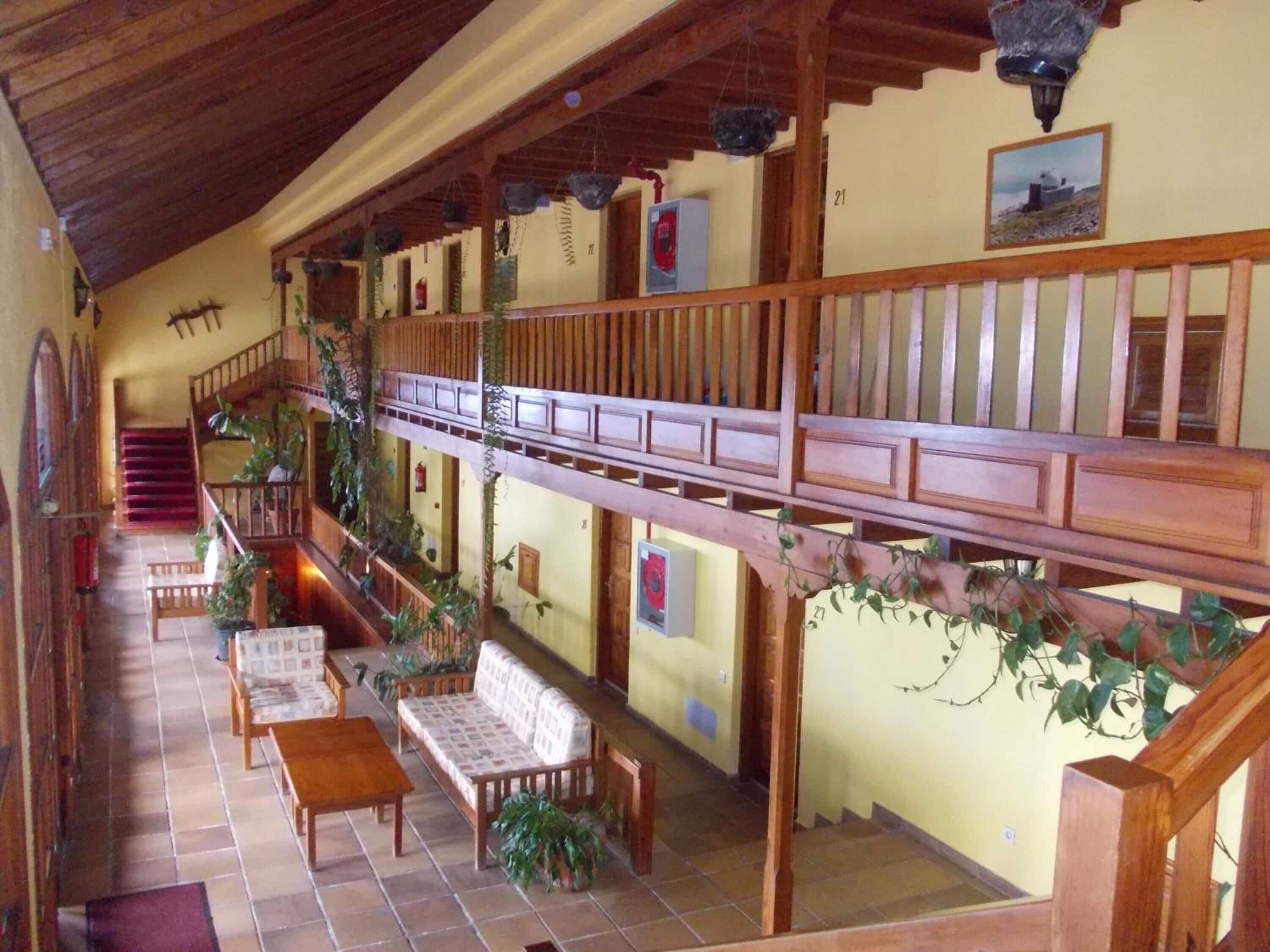 A spacious interior with a wooden staircase, a balcony with a railing, and a seating area with a sofa and a table.