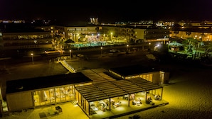 Een hotel aan het strand met een overdekt terras, diverse zwembaden en een strandbar.