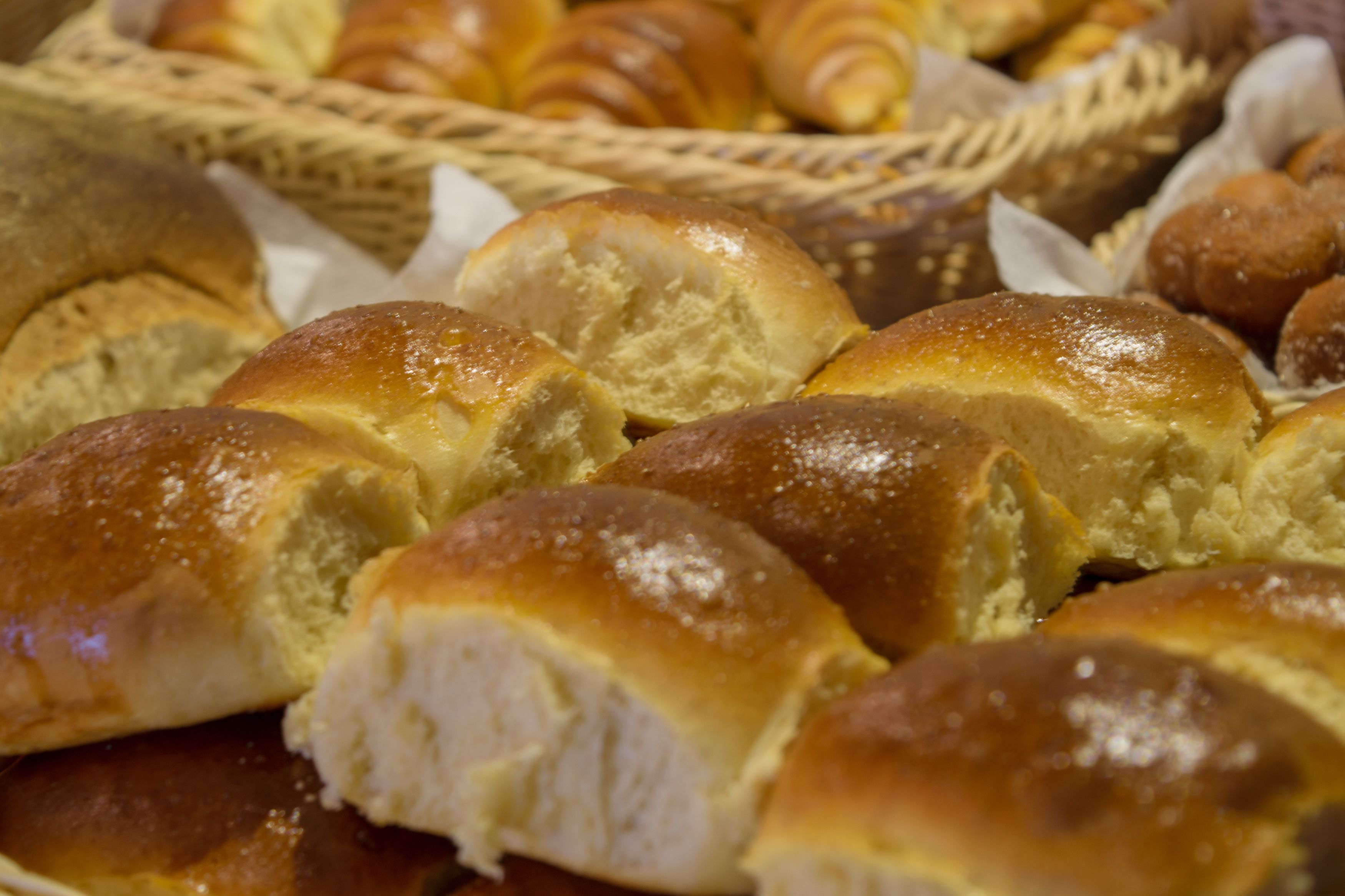 A variety of baked goods, including bread rolls and croissants, displayed in baskets.