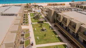Een resort met uitzicht op het strand, meerdere balkons en een centrale binnenplaats met een zwembad.