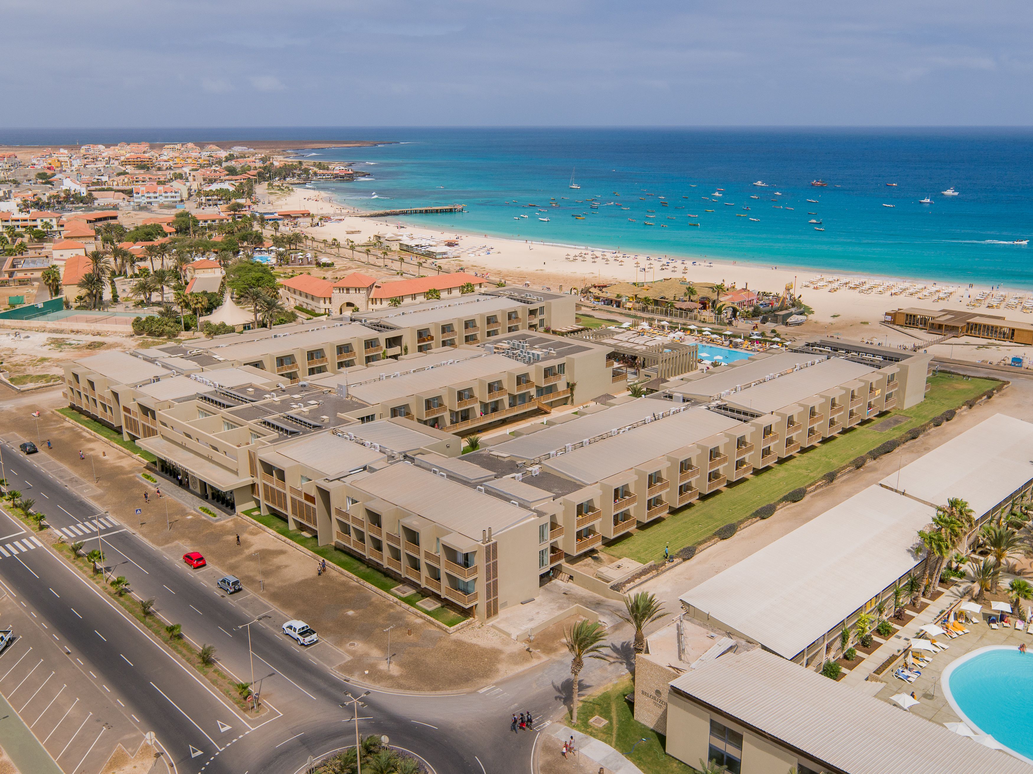 A hotel with multiple floors, a swimming pool, and a beach view.