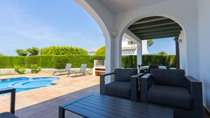 A covered outdoor area with a pool, lounge chairs, and a table. - Villas Finesse (Alayor)
