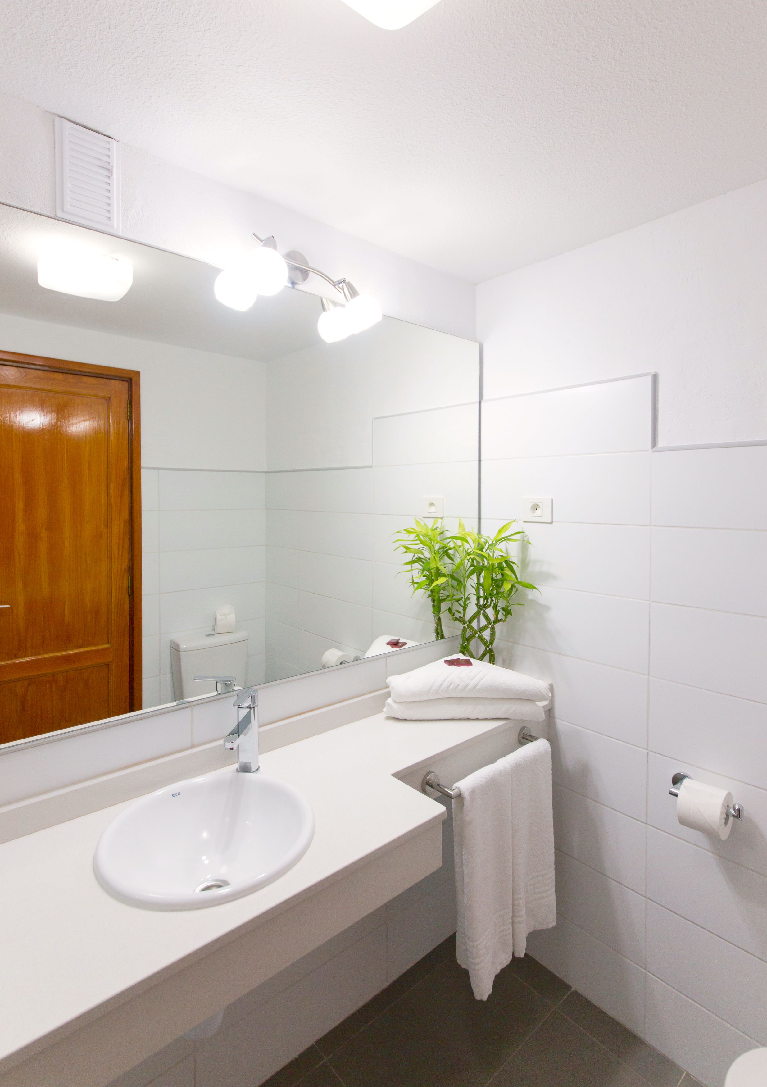 A bathroom with a white sink, mirror, and a toilet.