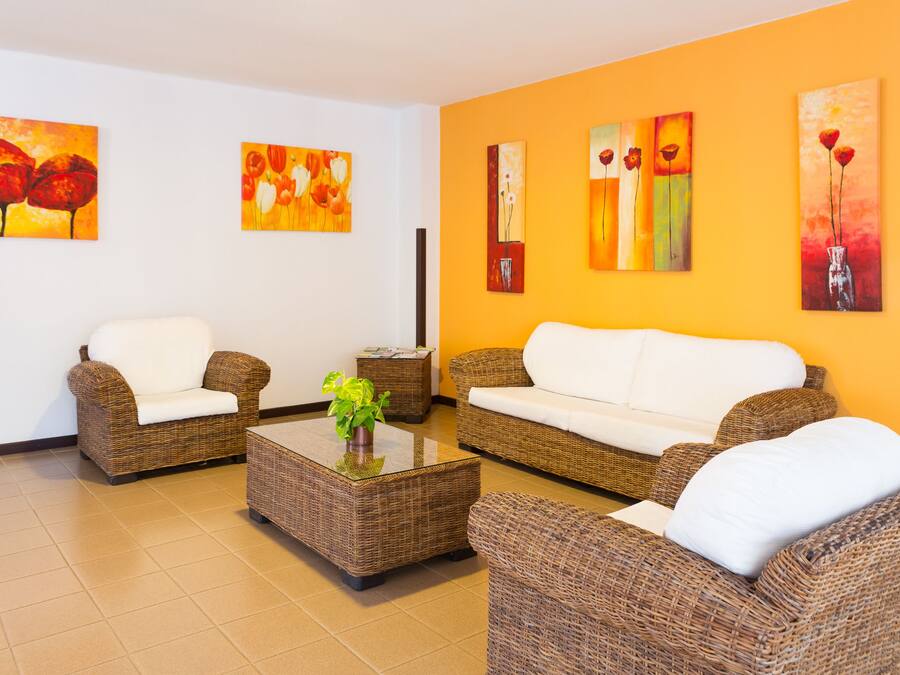 A room with wicker furniture, a white sofa, and artwork on the walls.