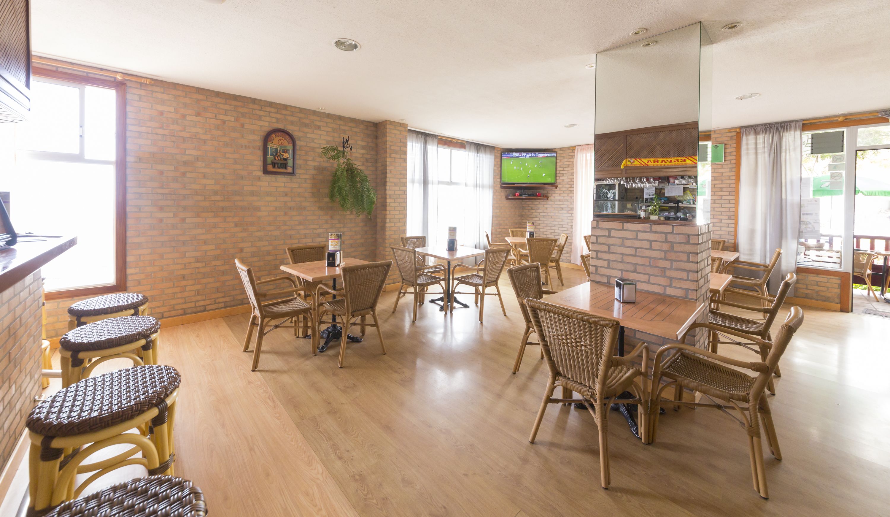 Una habitación amplia con pared de ladrillo, una mesa grande con sillas y una pantalla de televisión.