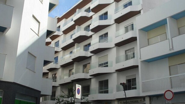 A multi-story building with balconies, a commercial sign, and a no parking sign. - Atlantic Side (Silves)