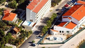 Vista aérea de un hotel con varias edificaciones, un estacionamiento y una piscina.
