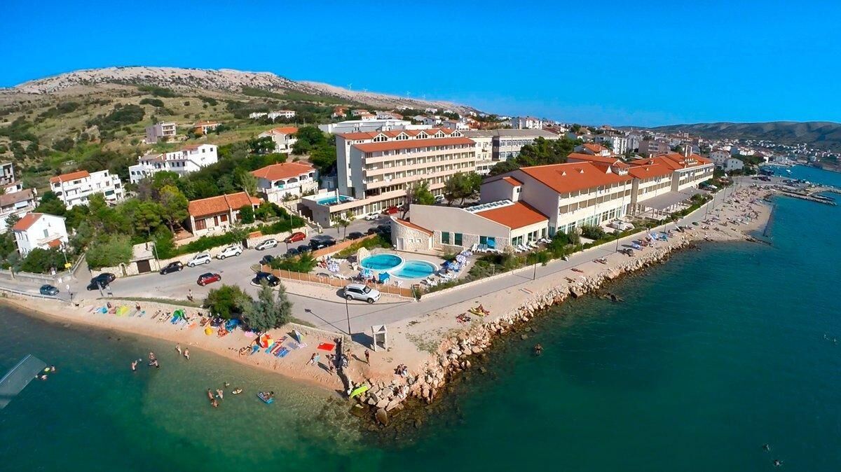 A coastal hotel with multiple buildings, a swimming pool, and a beach area.