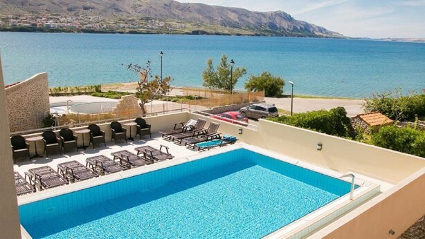 Una piscina en la azotea con sillones de descanso y vistas a un lago y montañas.