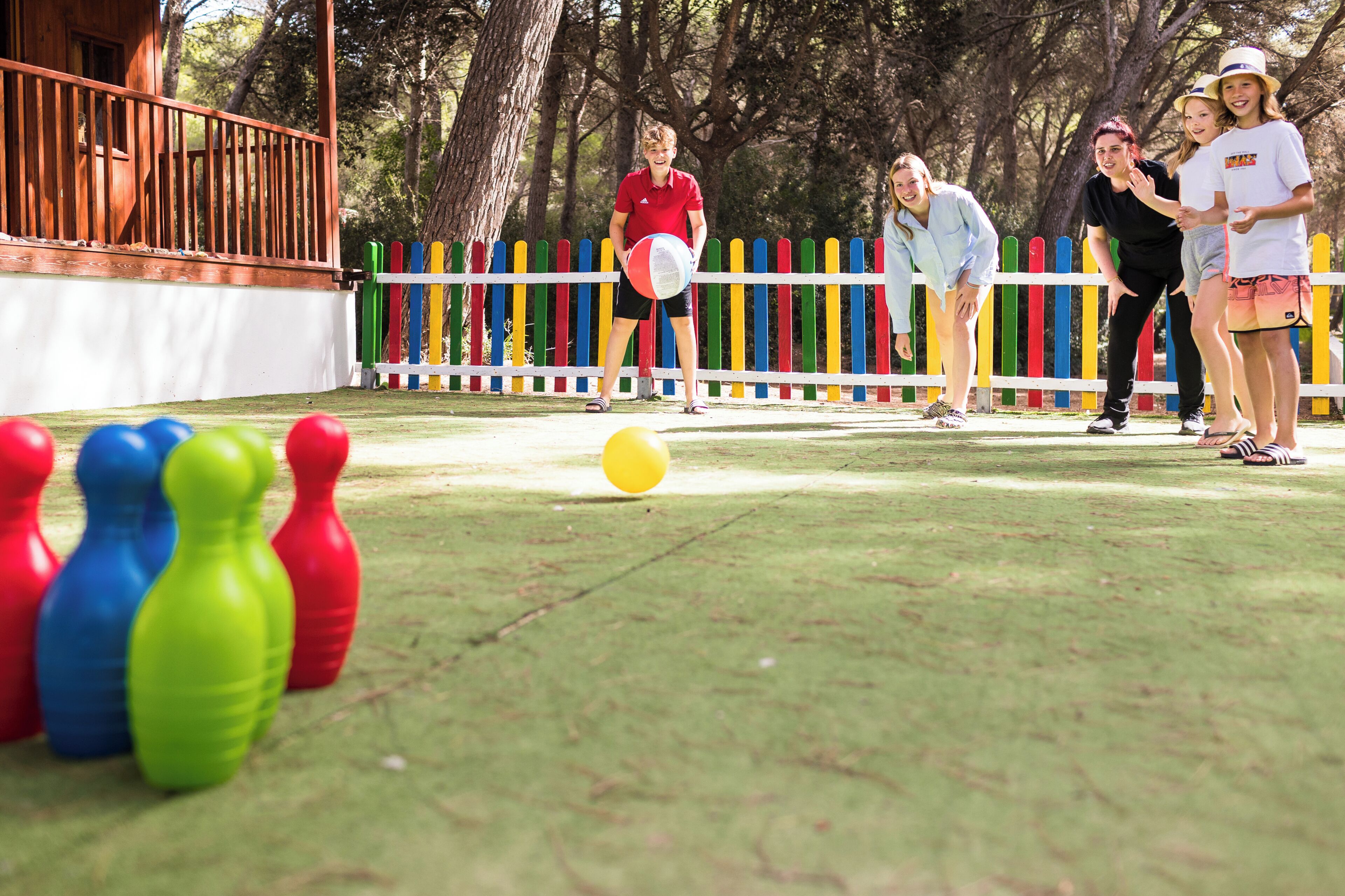 Un grupo de personas jugando un juego con fichas de colores y una pelota amarilla en un campo cubierto de hierba.