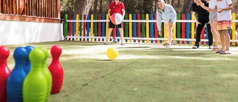 Un grupo de personas jugando un juego con fichas de colores y una pelota amarilla en un campo cubierto de hierba.