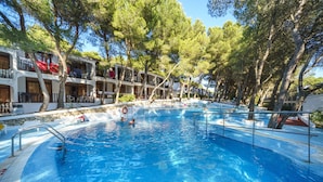 A swimming pool surrounded by trees and a building with balconies. - Aparthotel Sol Parc (Mercadal)