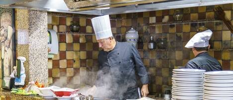 A chef cooking in a kitchen with a tiled backsplash and stainless steel appliances.