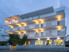 Un hotel de varios pisos con balcones, una pared de piedra y un restaurante en la planta baja.