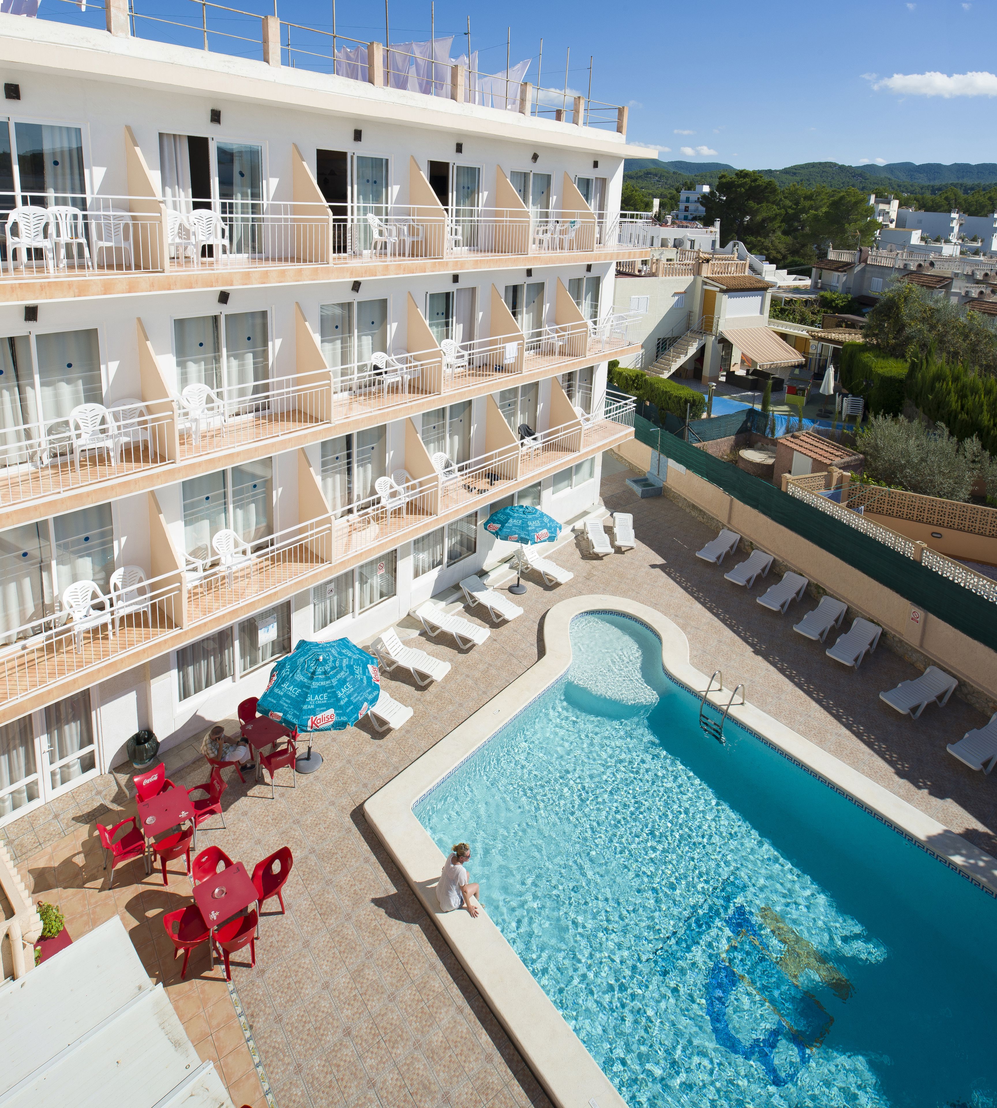 Un hôtel à plusieurs étages doté de balcons, d’une piscine et de chaises longues.