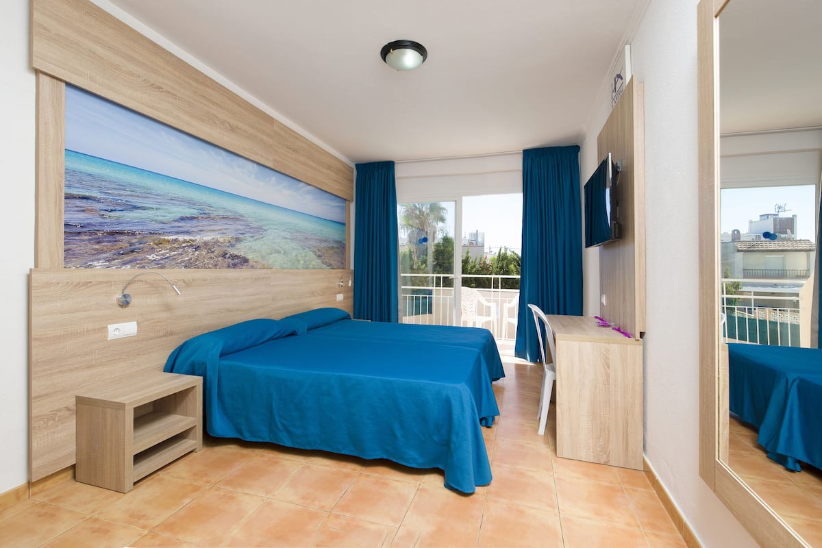 Een hotelkamer met een bed, een bureau, een groot schilderij en een balkon met uitzicht.