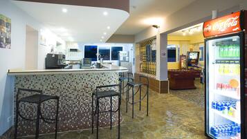 A bar area with a tiled backsplash, a refrigerator stocked with beverages, and a television screen.