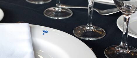 A table set with white plates, clear wine glasses, and a silver fork.