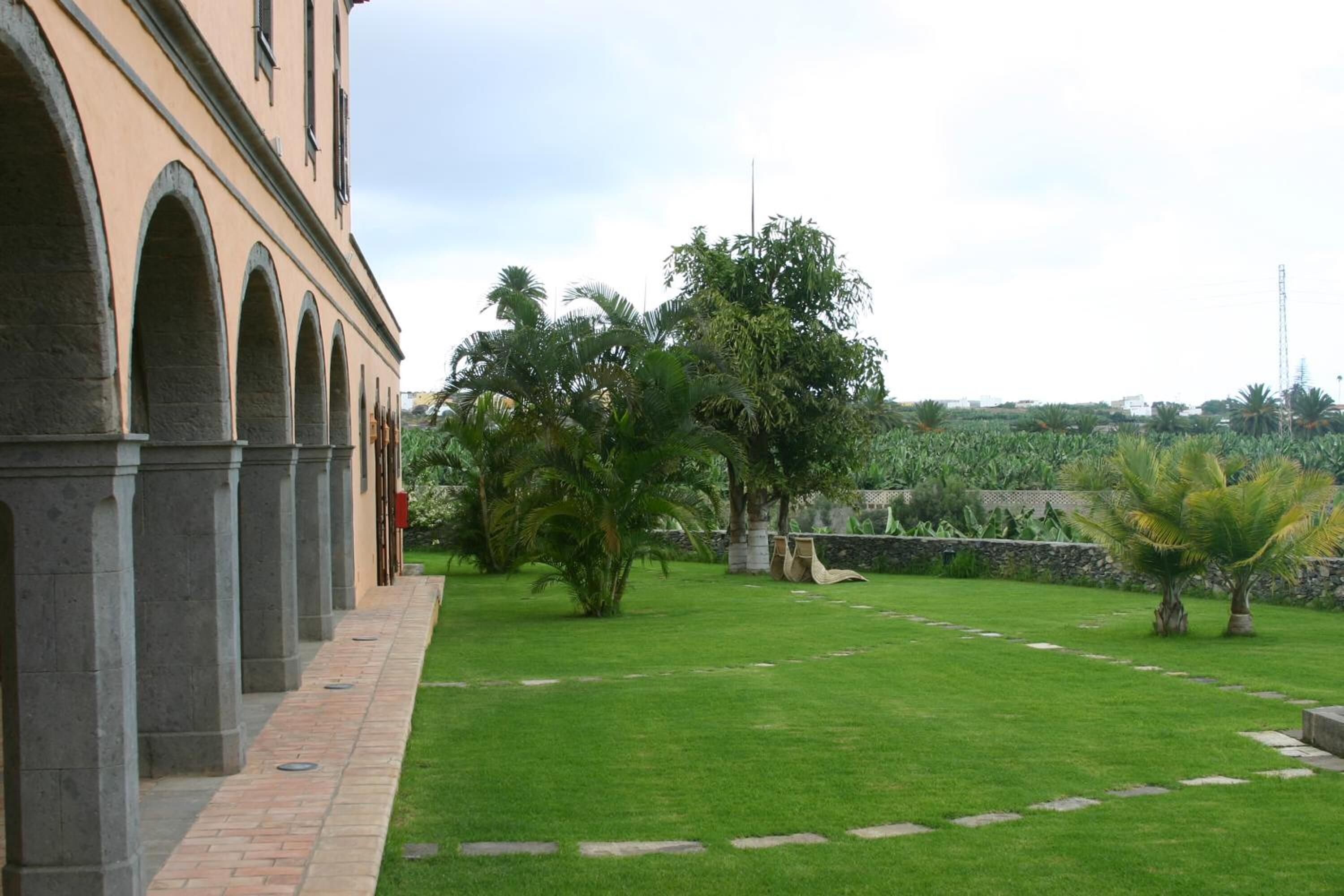 Un patio con sendero adoquinado, césped verde y un edificio con arcos.