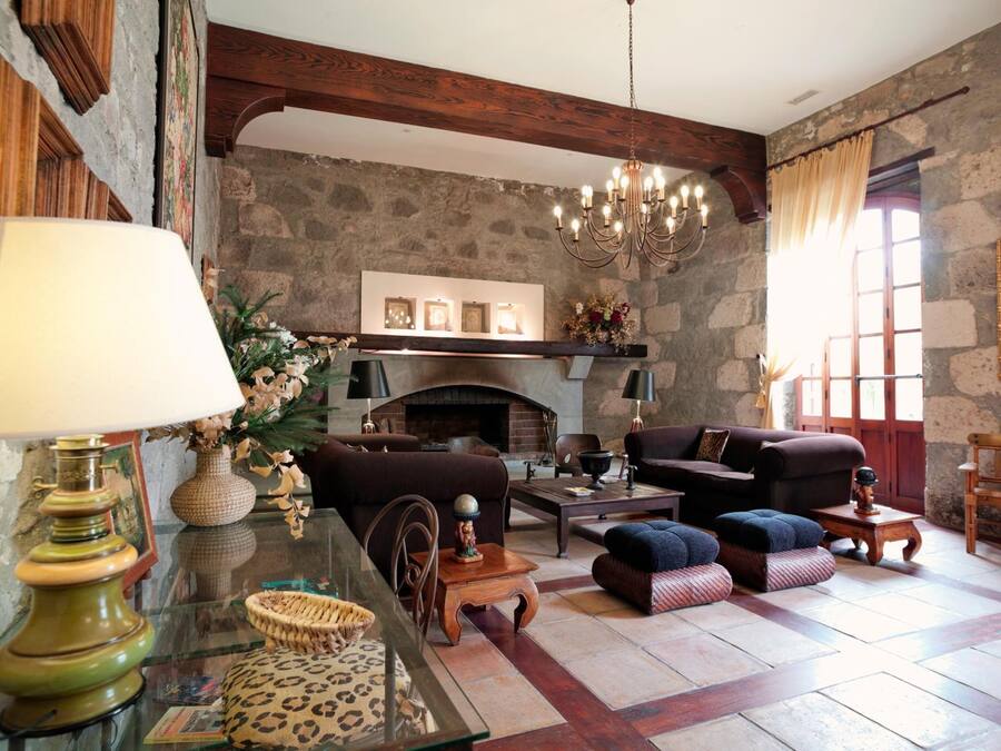 Una sala de estar acogedora con chimenea, vigas de madera y un candelabro.