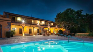 Um hotel com piscina, área de estar externa e um pátio bem iluminado.