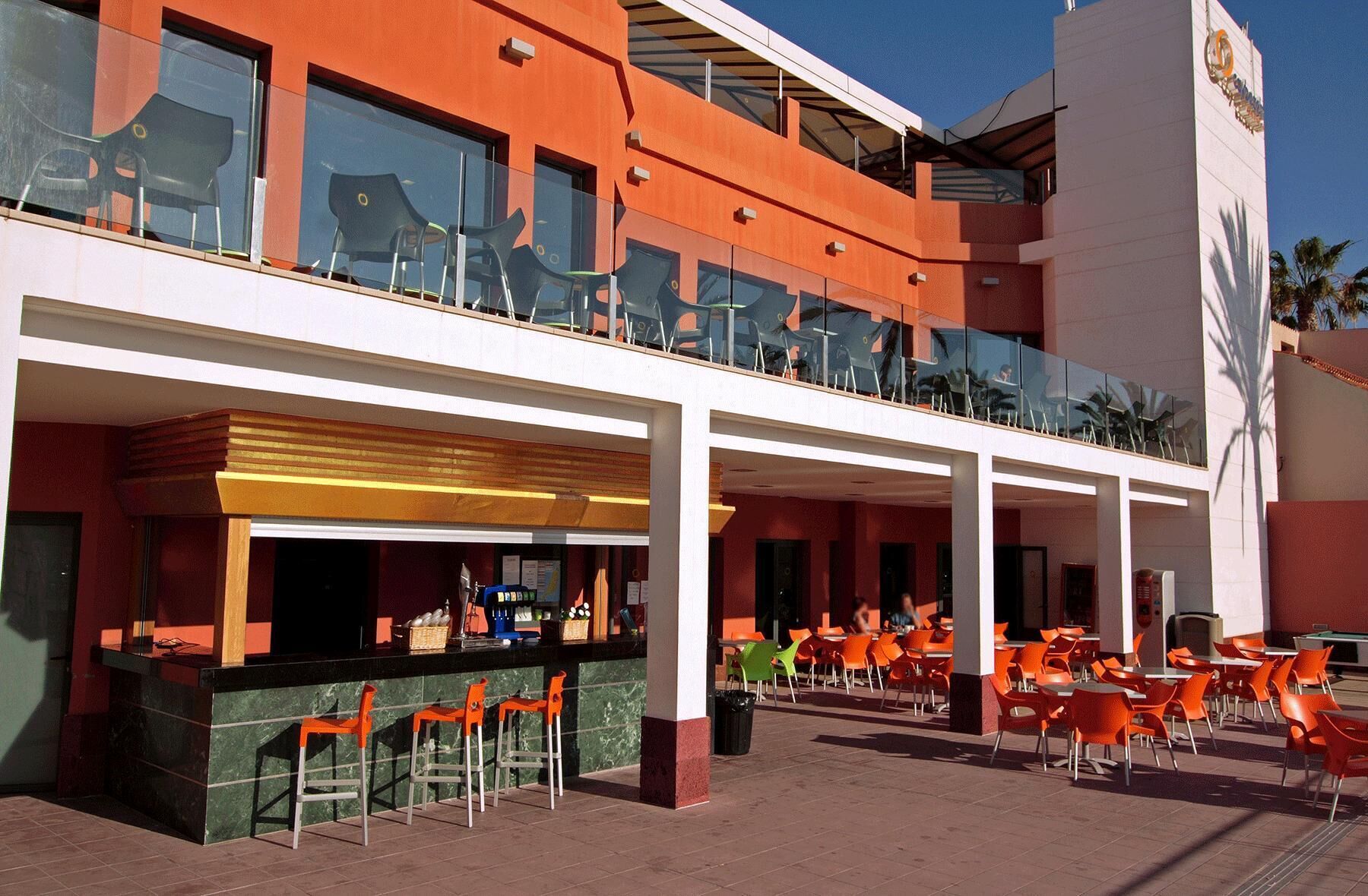 A hotel with outdoor seating, a bar area, and a poolside view.