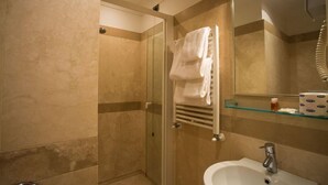 Un baño con cabina de ducha de vidrio, un lavabo y un perchero para toallas.