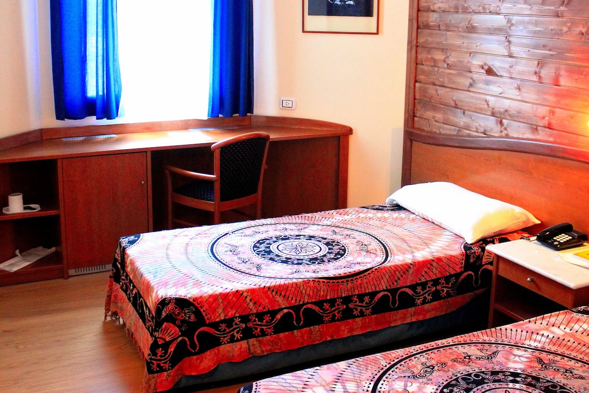 A hotel room with two beds, a desk, and a chair.