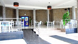 Un vestíbulo amplio con una pared de piedra, un mostrador de recepción y una escalera que conduce a los pisos superiores.