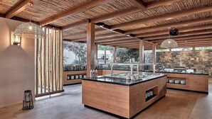 A modern kitchen with a central island, wooden beams, and a stone wall. - Lambi (Malevizi)