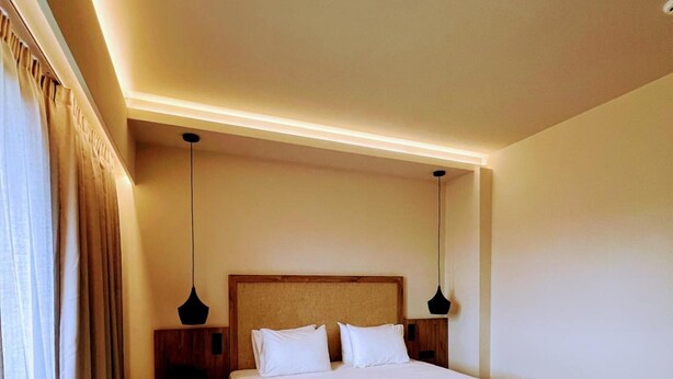 A hotel room with a large bed, two bedside tables, and a headboard. - Lambi (Malevizi)