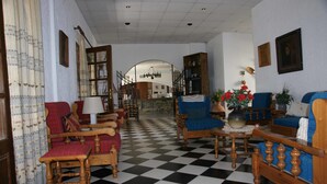 Piso xadrez, móveis de madeira e um lustre.