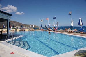 Alberca al aire libre, sombrillas en la alberca y camastros