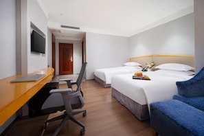A hotel room with a wooden desk, two beds, a blue armchair, and a television. - Kaiserdom Hotel Ouzhuang Huayue (Guangzhou)