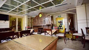 Un restaurant avec un plafond haut, des panneaux de verre décoratifs, des meubles en bois et une horloge au mur.
