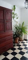 Una habitación con un armario de madera, plantas en macetas y un suelo a cuadros.