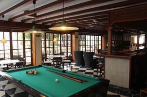 Mesa de billar con bolas, zona de bar y asientos exteriores con vistas.