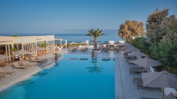 A resort pool with lounge chairs and umbrellas, overlooking the sea. - Kathrin Beach Hotel (ADELIANOS KAMPOS)