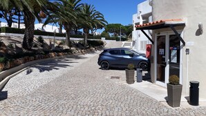 Uma entrada pavimentada que leva a um edifício, com um carro estacionado na frente.