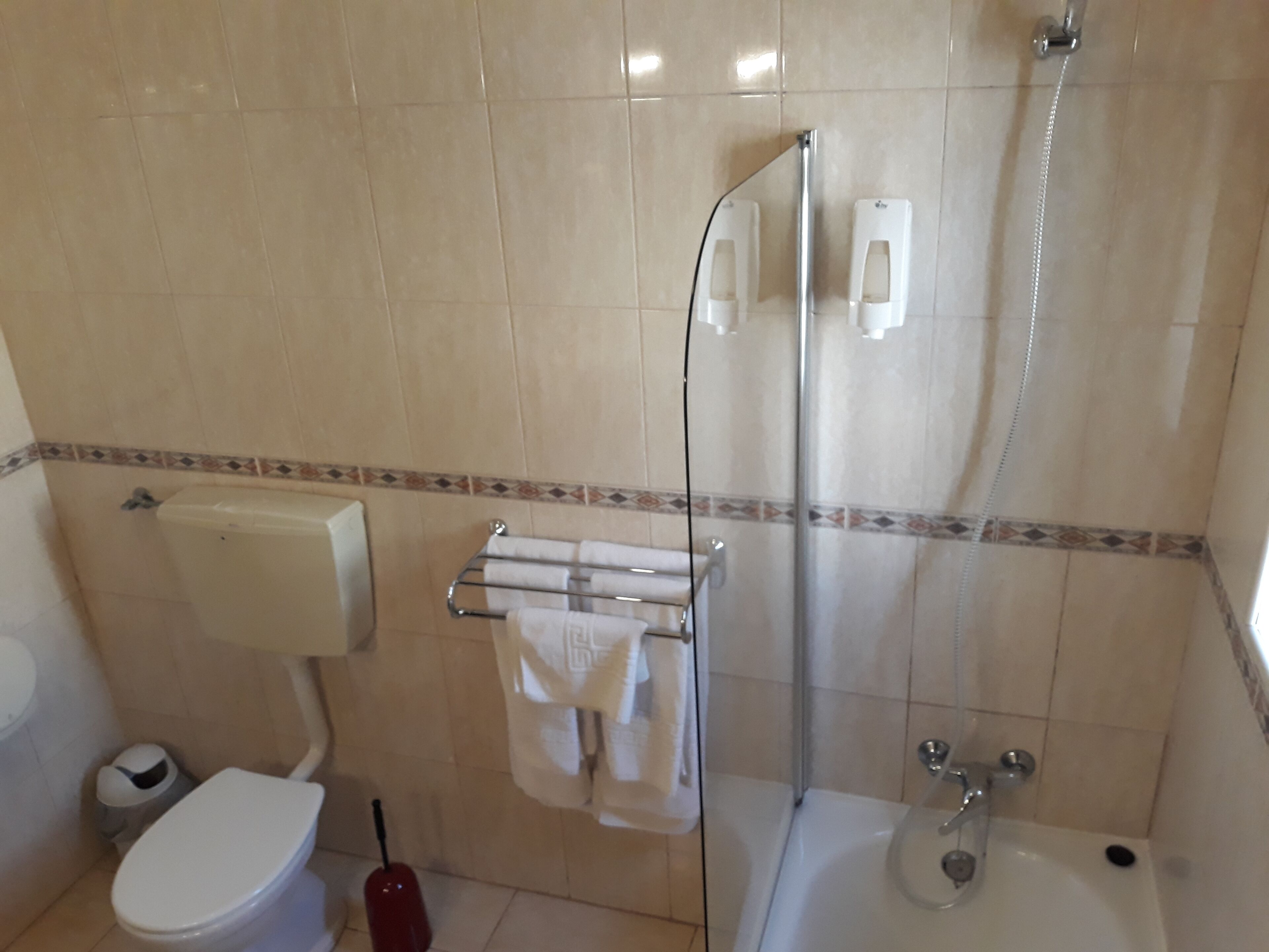 A bathroom with a toilet, a glass-enclosed shower, and a bathtub.