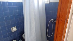 A bathroom with blue tiles, a shower, a toilet, and a wooden door. - Apartments Villa Frangis (Corfu)