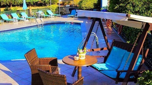 Una piscina con sillas de descanso y una mesa.