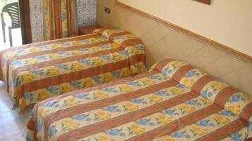 A room with two beds with floral bedding, a chair, and a patterned wall.