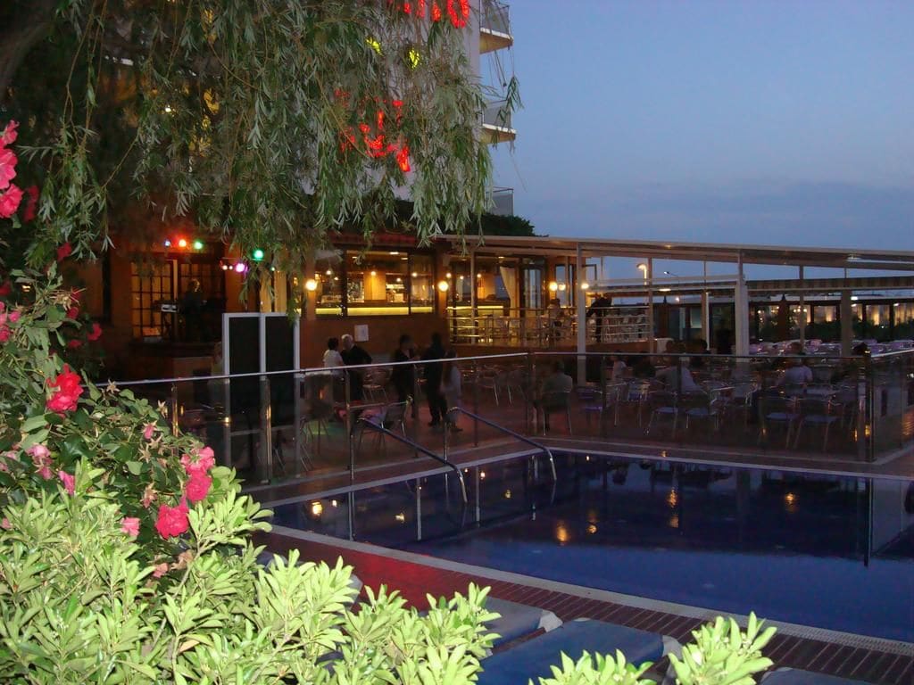 A pool area with seating and a restaurant in the background.