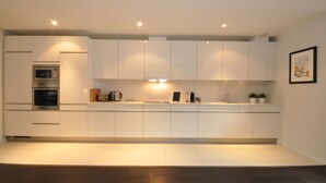 Una cocina moderna con armarios blancos, electrodomésticos integrados e iluminación empotrada.