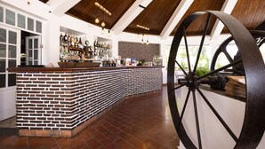 A bar area with a brick counter, wooden ceiling beams, and a large metal wheel. - Quinta do Morgado - Monte da Eira (Tavira)