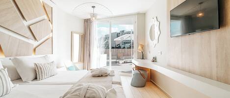 Habitación de hotel moderna con una cama grande, un televisor montado en la pared y vistas al exterior.
