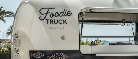 Un camion-restaurant arborant les marques « Foodie Truck » et « Street Food », proposant un menu avec des options de « sushis » et de « ceviches », et affichant le slogan « Mangez bien, sentez-vous bien ».