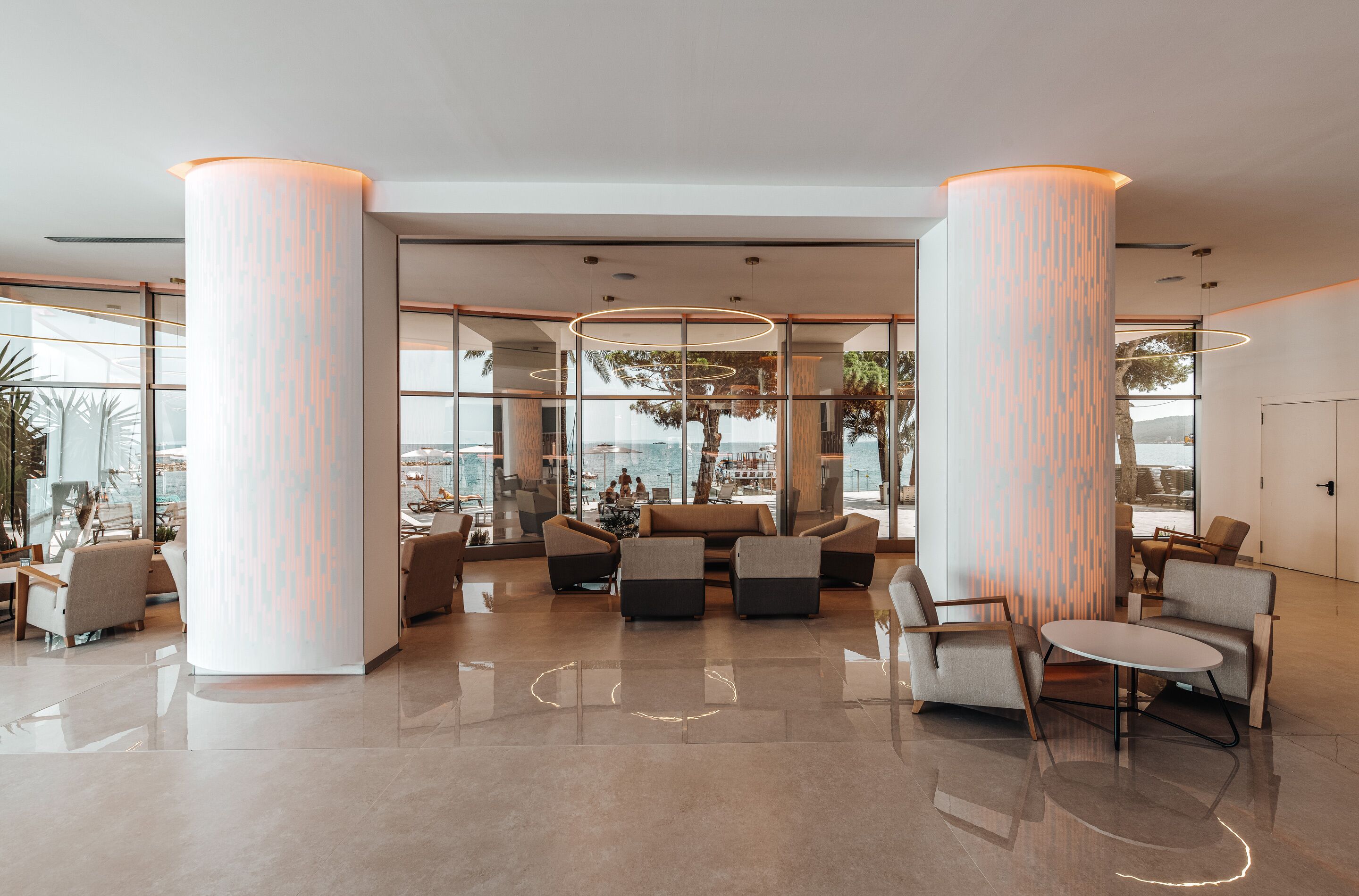 A spacious lobby with high ceilings, large columns, and a view of the sea.