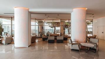 A spacious lobby with high ceilings, large columns, and a view of the sea.